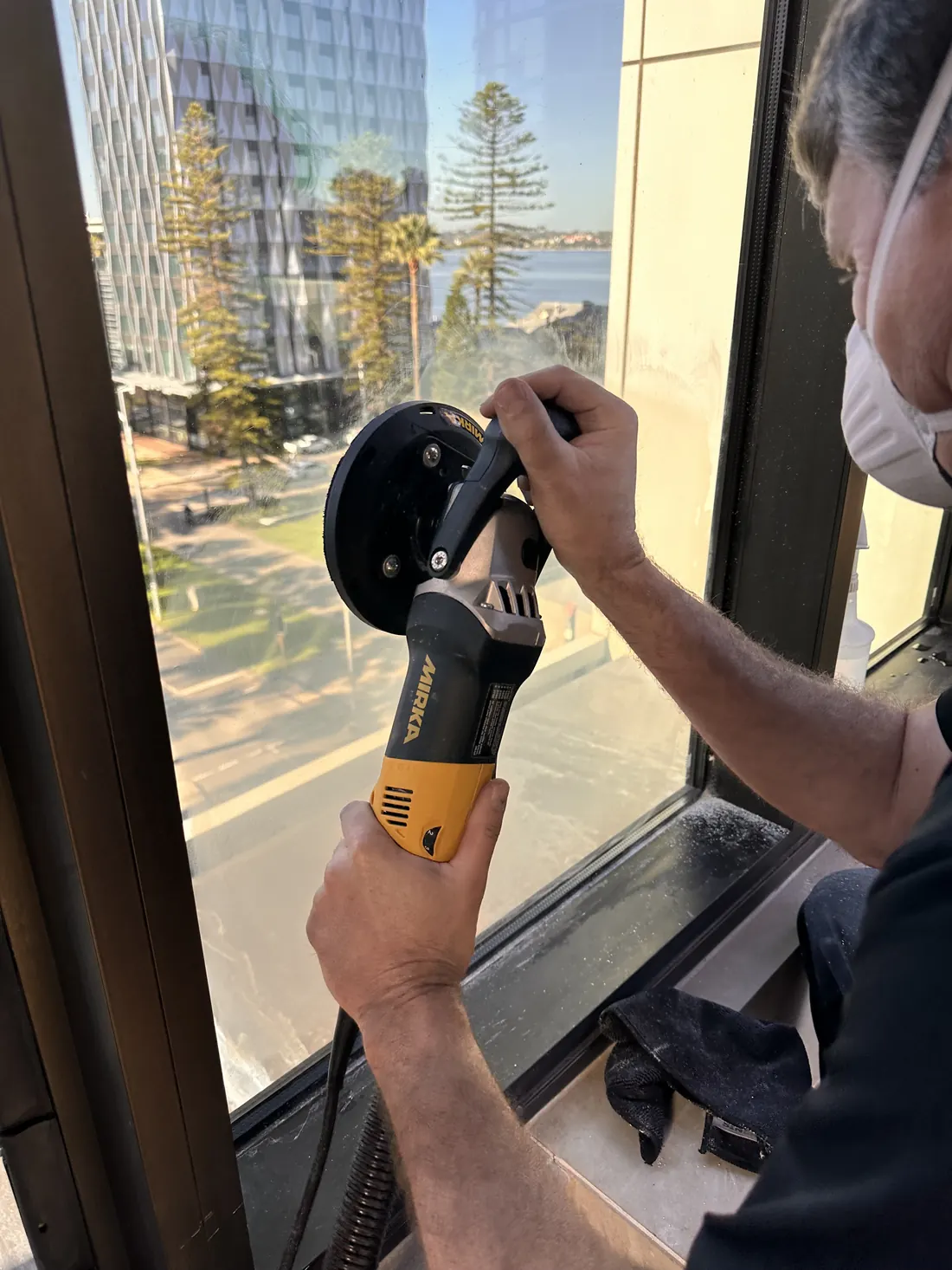 Rotary polisher with dust extraction working across a corroded window pane